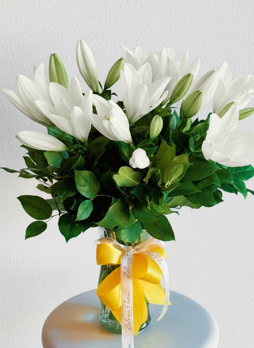 Bouquet of white flowers with green leaves in a clear vase on a white background