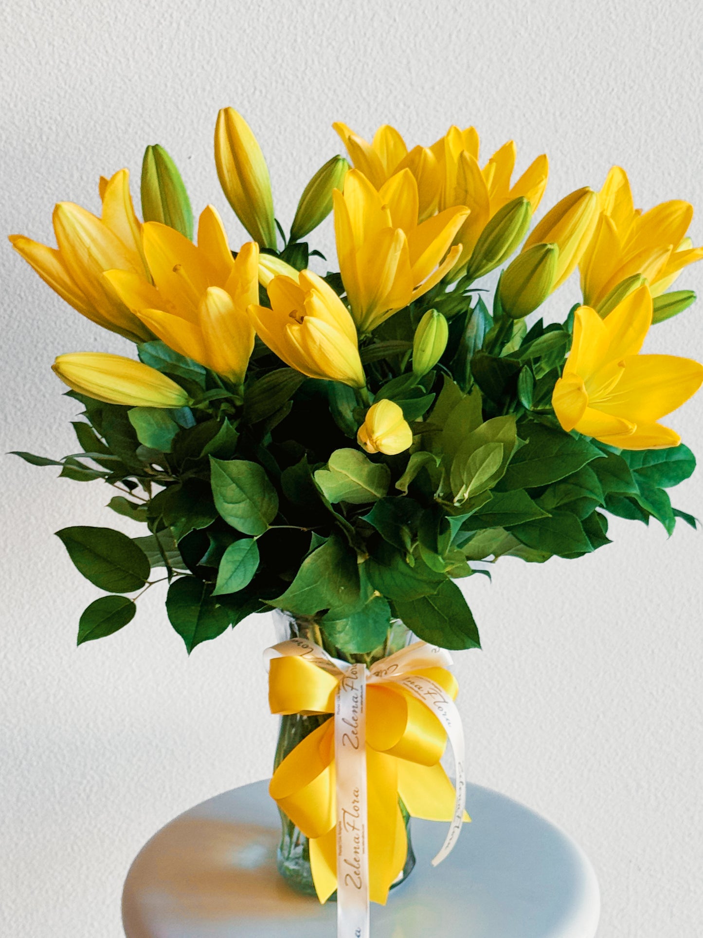 Bouquet of yellow lilies with green leaves on a white background