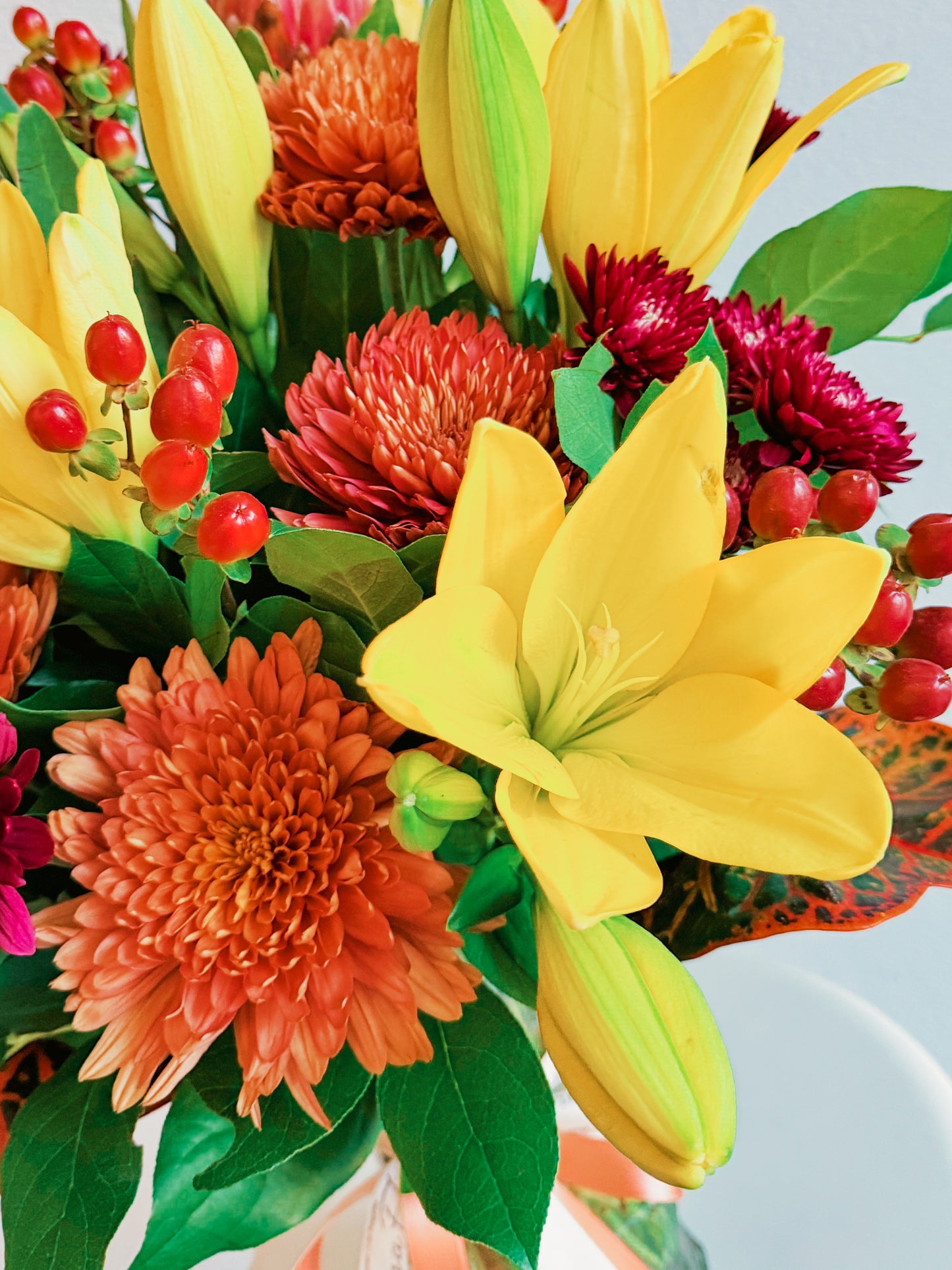 Colorful bouquet of flowers with yellow, orange, and red flowers on a light blue background