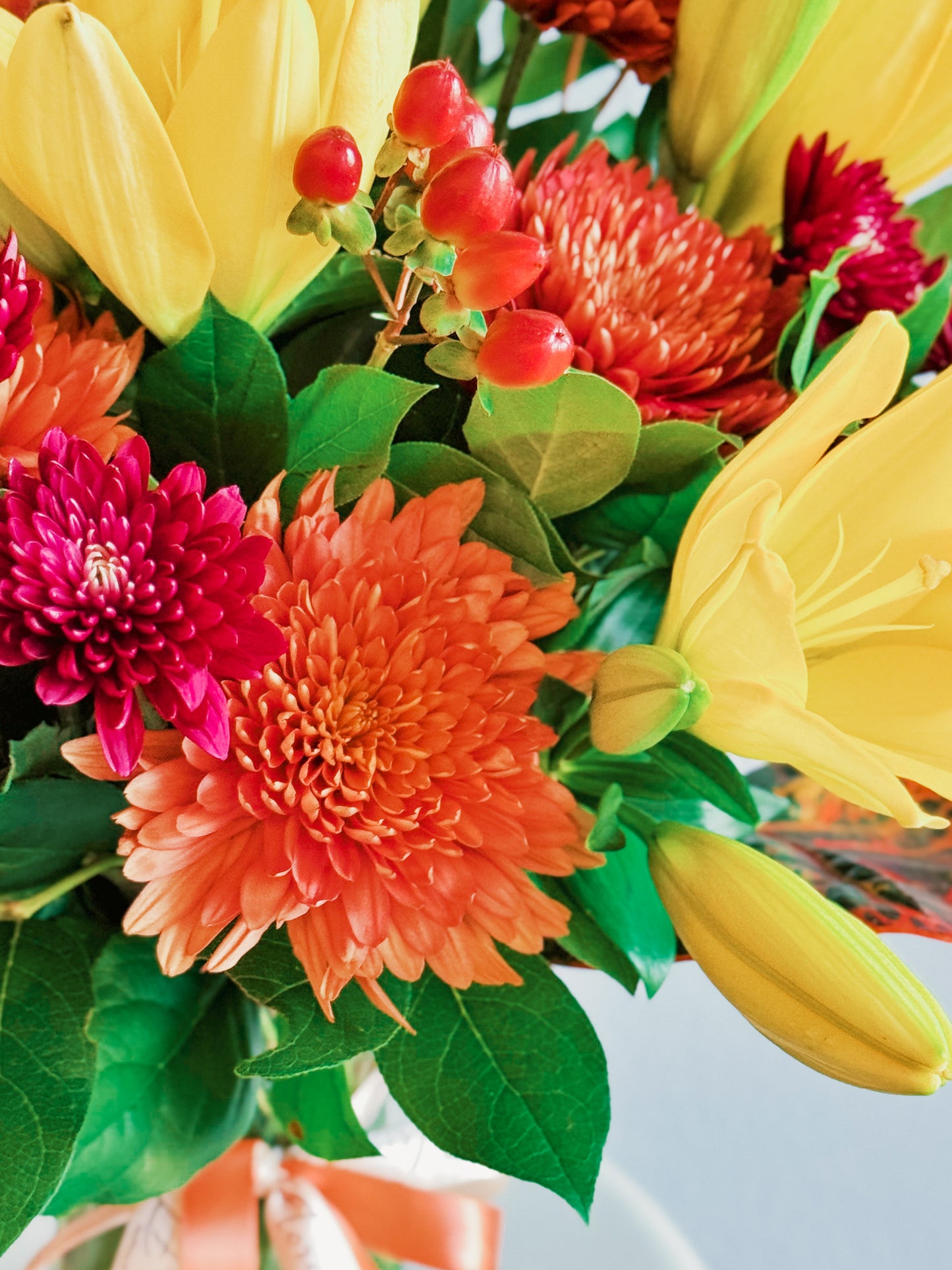 Bouquet of colorful flowers including yellow, red, and orange with green leaves.