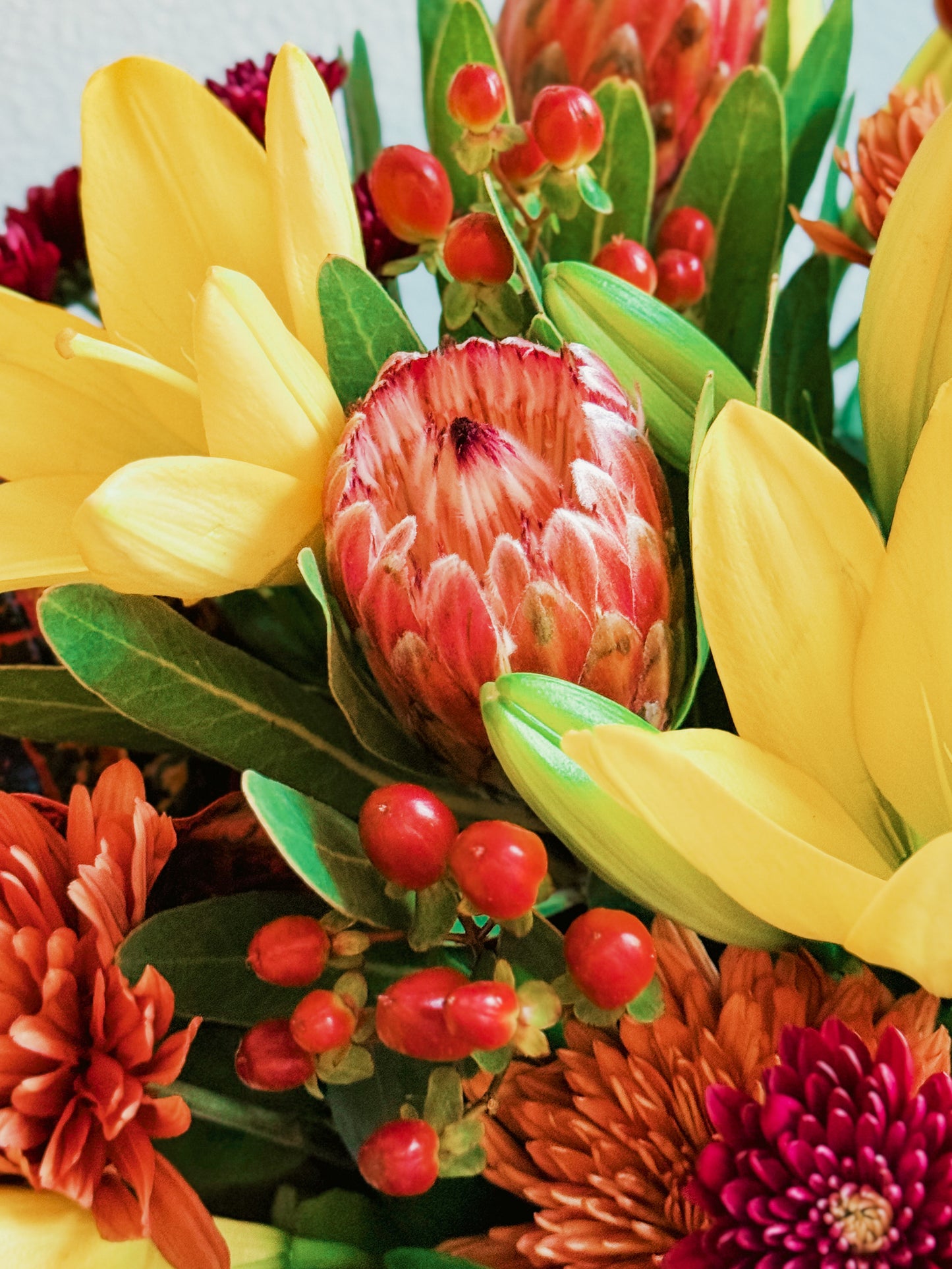 Bouquet of colorful flowers including yellow, red, and orange with green leaves.
