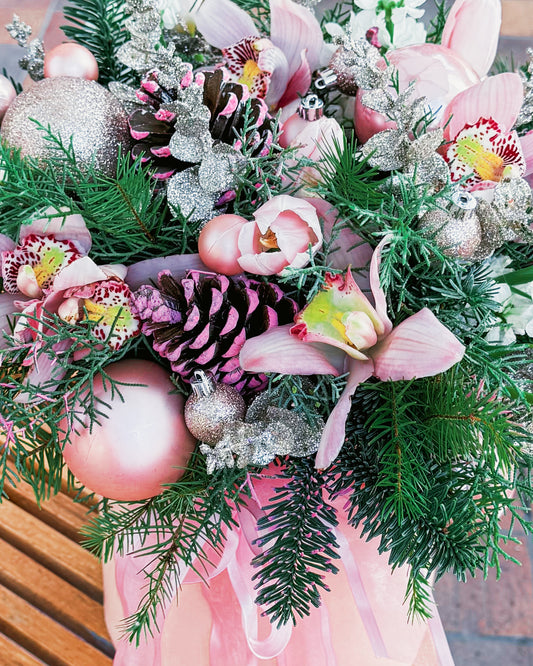 Decorative arrangement with flowers, ornaments, and greenery on a pink background