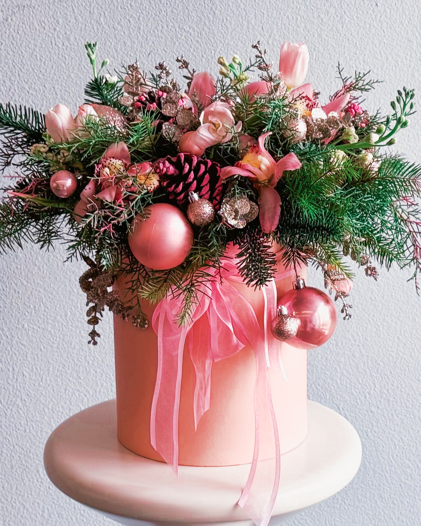 Decorative floral arrangement with pink ornaments and ribbons on a white background
