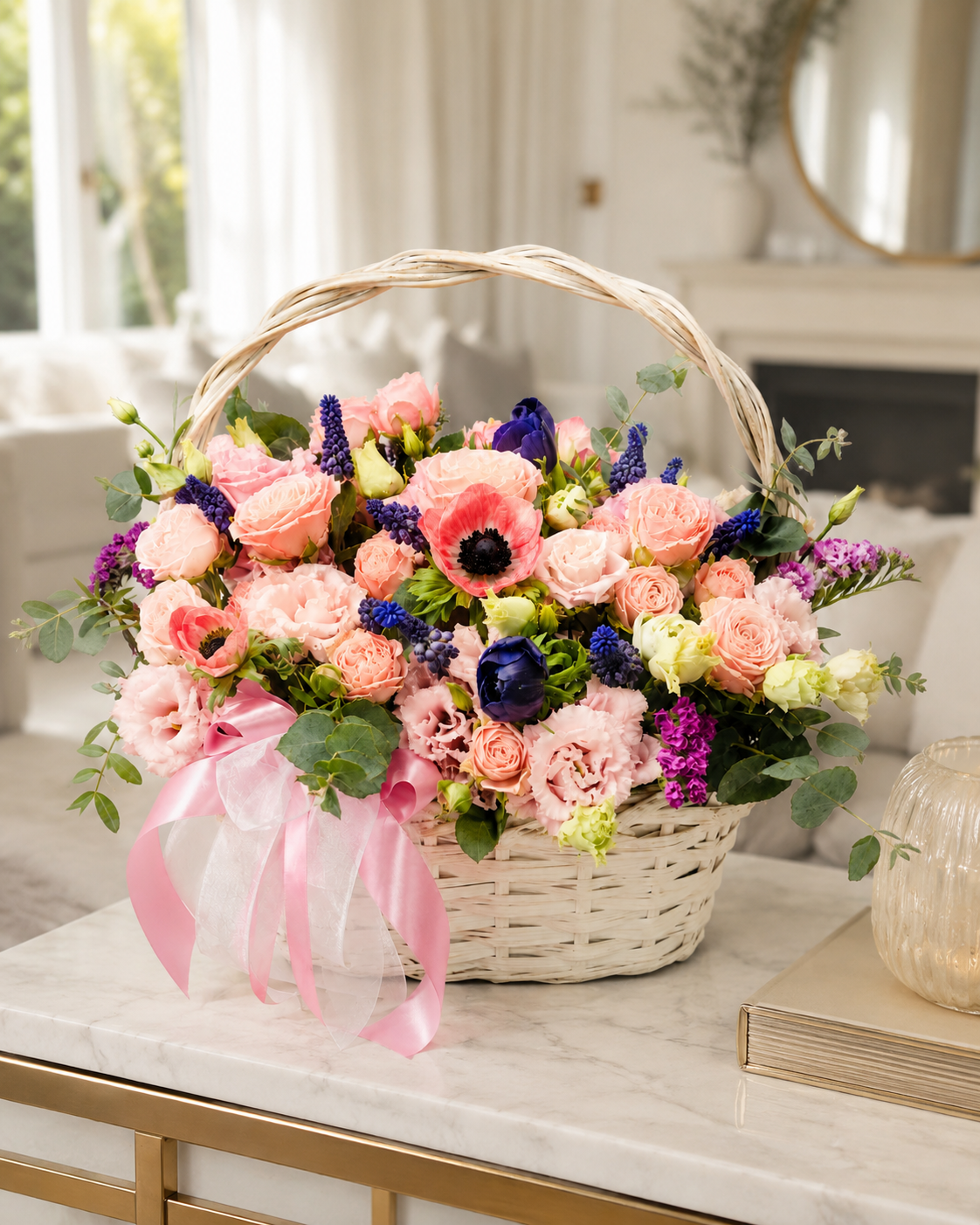 Pleasure Hampy floral basket with pink roses, anemones, blue and purple accents, eucalyptus, and pink ribbon in a bright home interior | Zelena Flora | Los Angeles