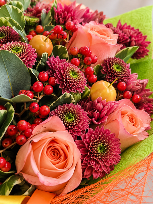 Close-up of Raspberry Heart bouquet with peach roses, raspberry chrysanthemums, red berries and green patterned wrap
