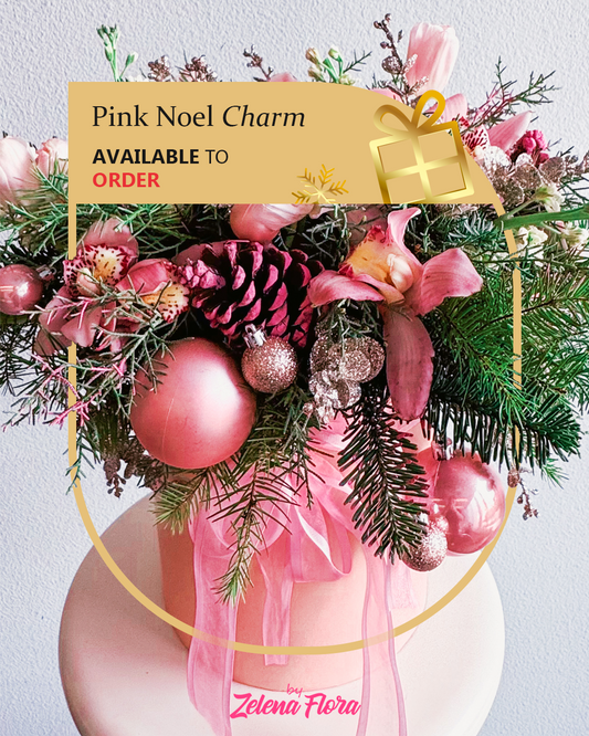 Decorative arrangement with pink ornaments and greenery, featuring a 'Pink Noel Charm' label.