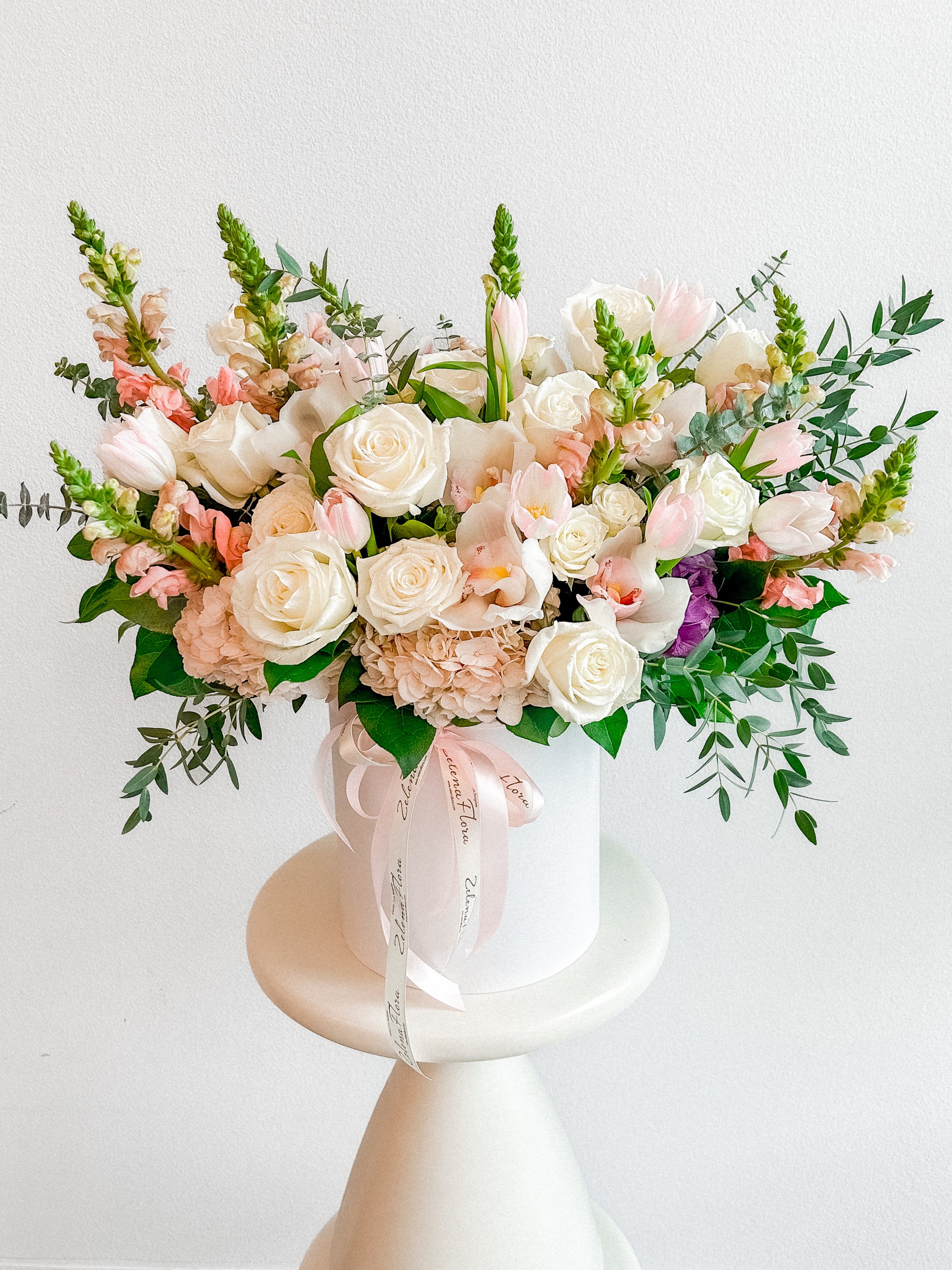 Blush Bliss flower box arrangement with creamy white roses, pink orchids, hydrangeas, dusty miller leaves, alstroemerias, and trailing amaranthus by Zelena Flora