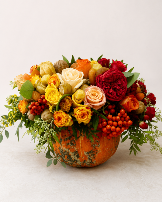 Flowers in a pumpkin centerpiece with red, yellow, and peach roses, physalis, rowan berries, and greenery | Zelena Flora | Los Angeles