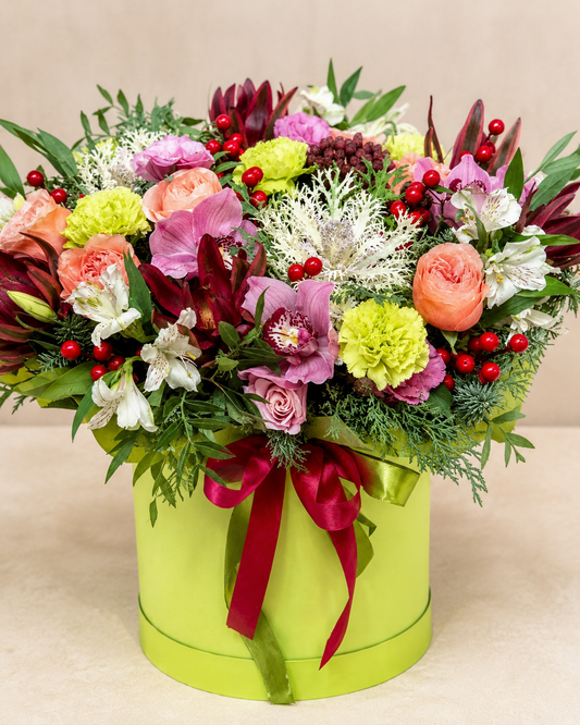 Festive Floral Ensemble flower box with roses, orchids, green carnations, red hypericum berries, winter greenery, lime hatbox, and burgundy ribbon | Zelena Flora | Los Angeles
