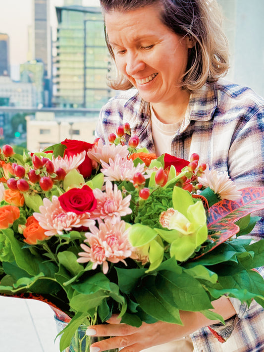 Person holding a large bouquet of flowers with a cityscape in the background