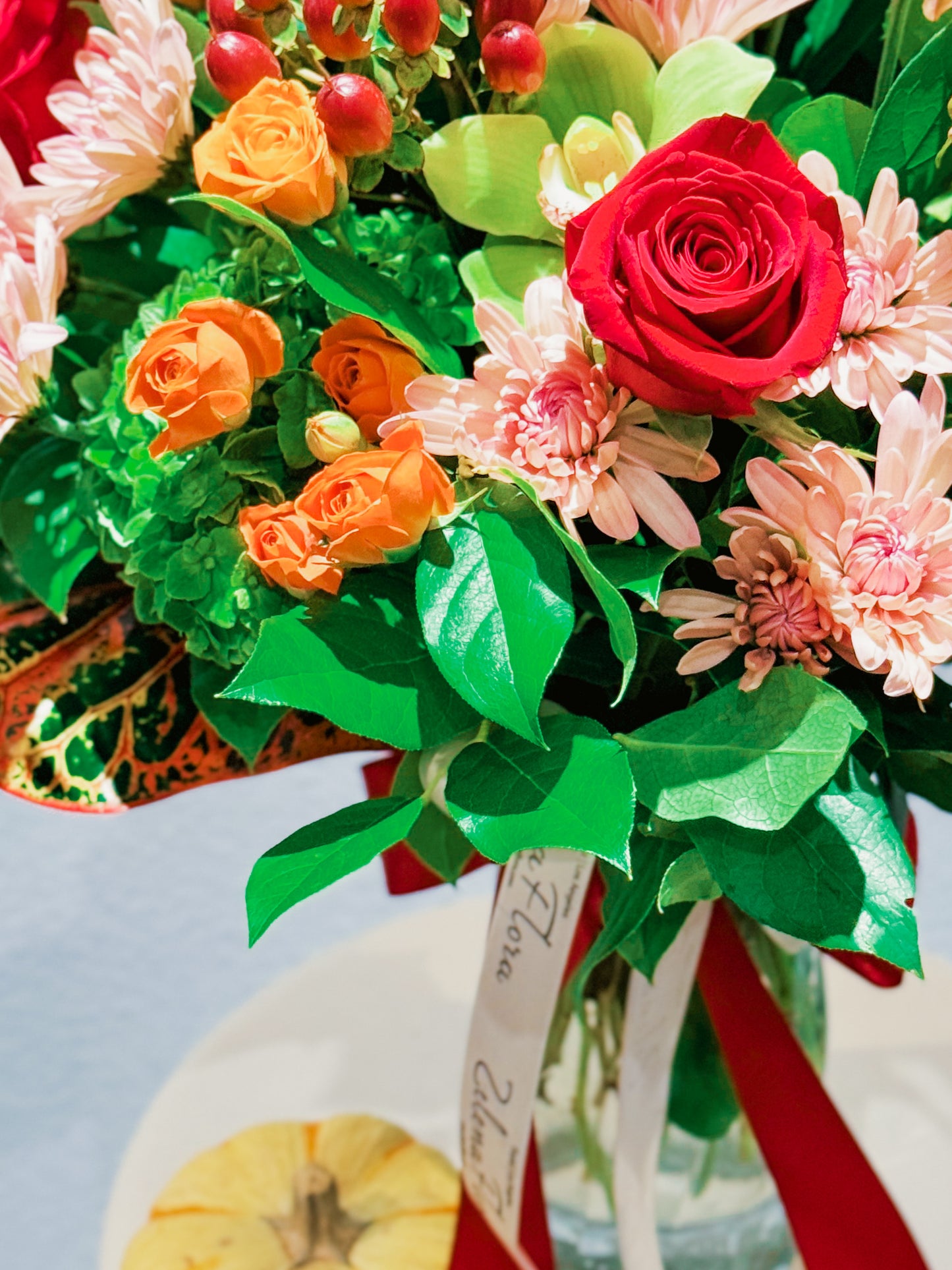 Bouquet of colorful flowers with a red ribbon on a light blue background