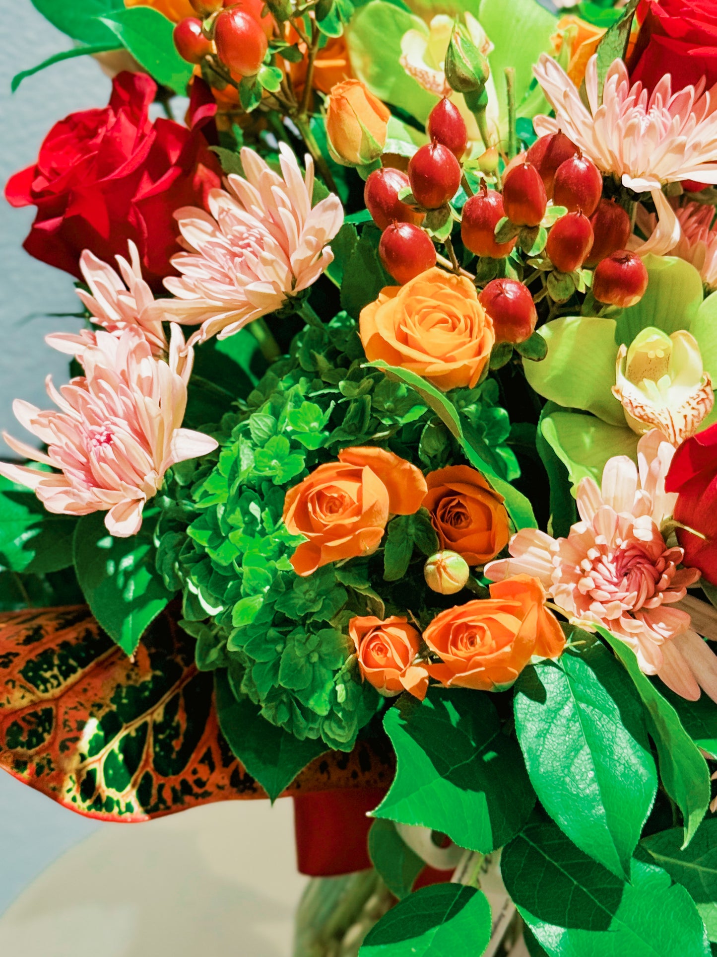 Bouquet of colorful flowers including red, orange, and pink flowers with green leaves.