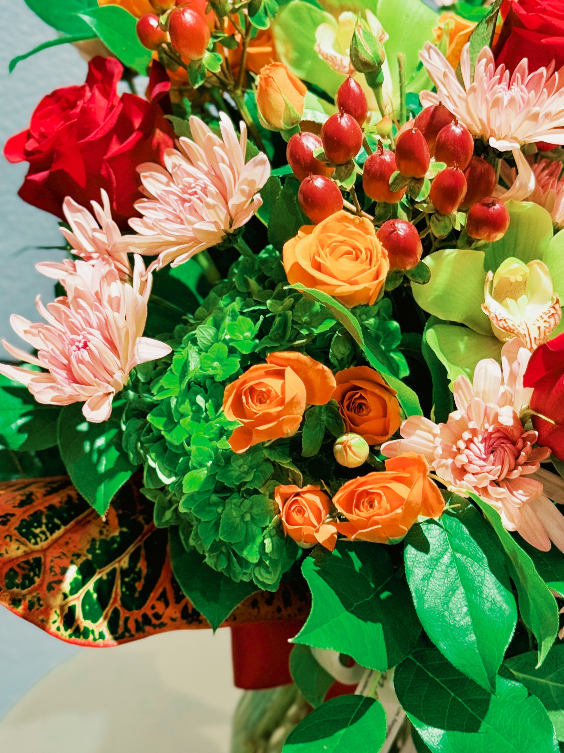 Bouquet of colorful flowers including red, orange, and pink flowers with green leaves.