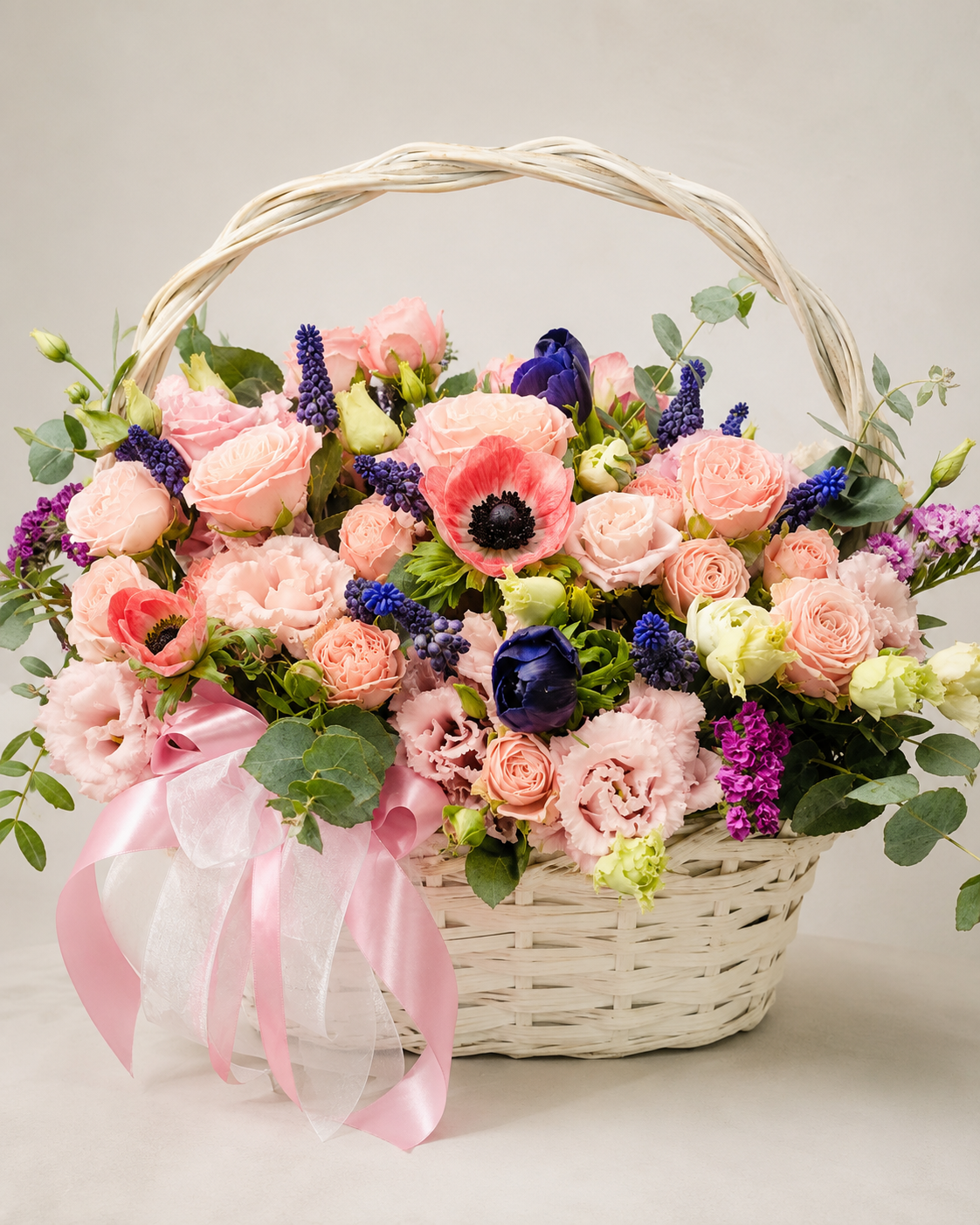 Pleasure Hampy floral basket with pink roses, ranunculus, coral anemones, blue muscari, purple snapdragons, eucalyptus, and pink ribbon | Zelena Flora | Los Angeles