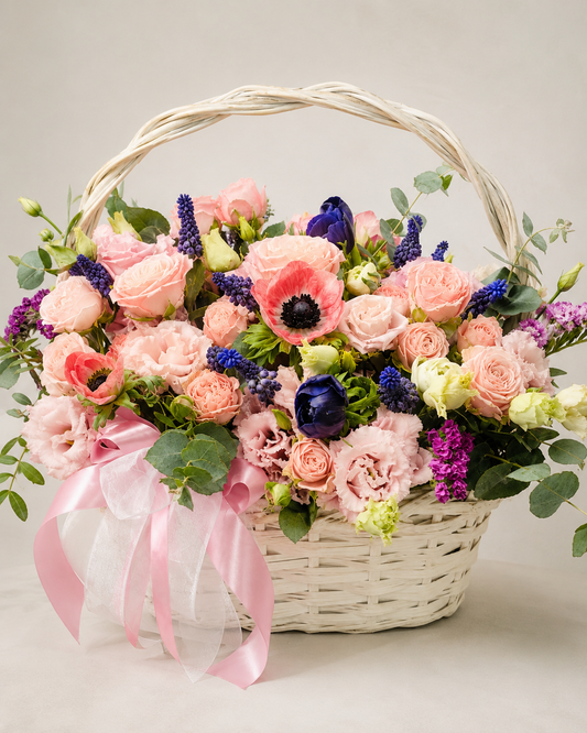 Pleasure Hampy floral basket with pink roses, ranunculus, coral anemones, blue muscari, purple snapdragons, eucalyptus, and pink ribbon | Zelena Flora | Los Angeles