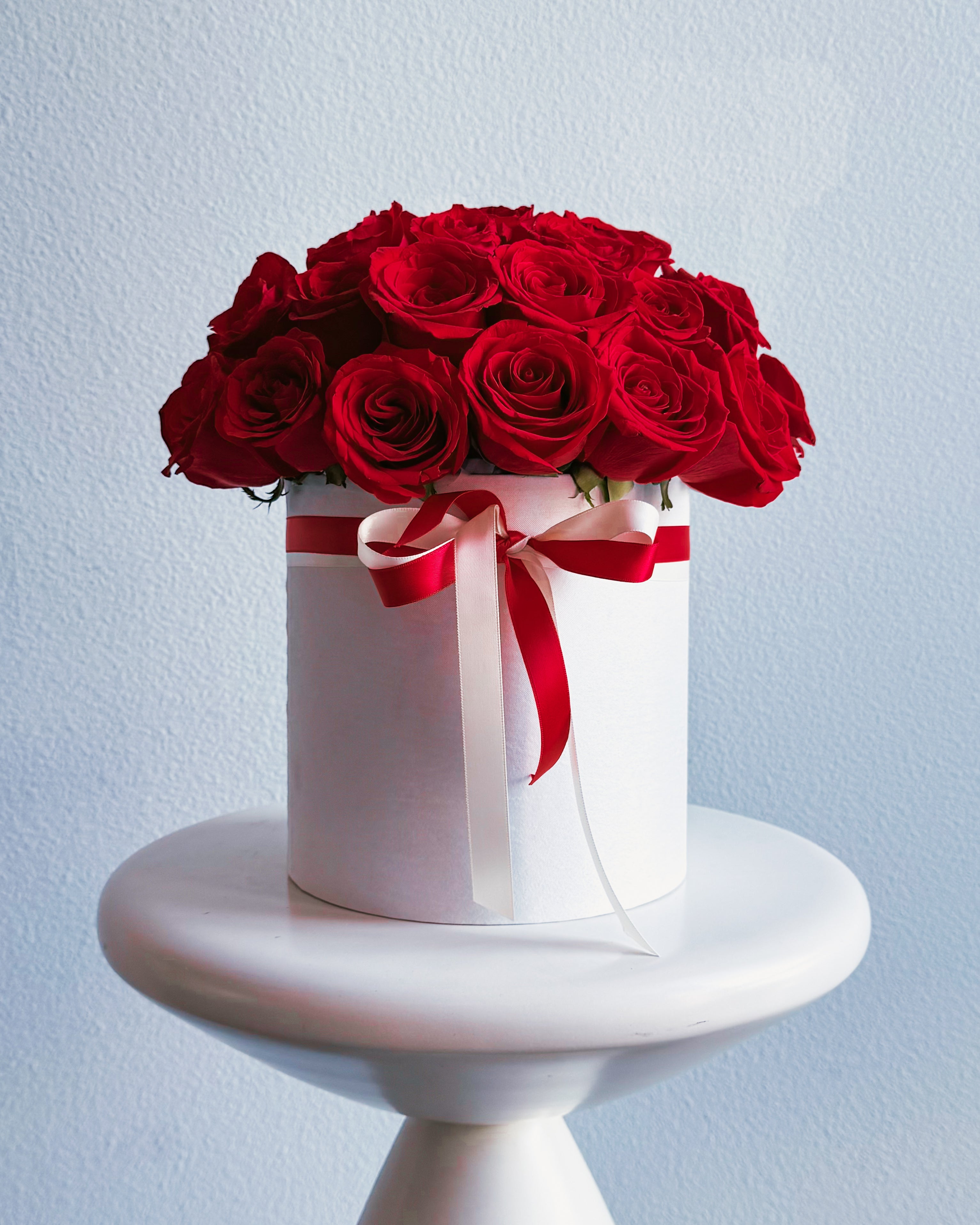 White box with red roses and a red ribbon on a light blue background