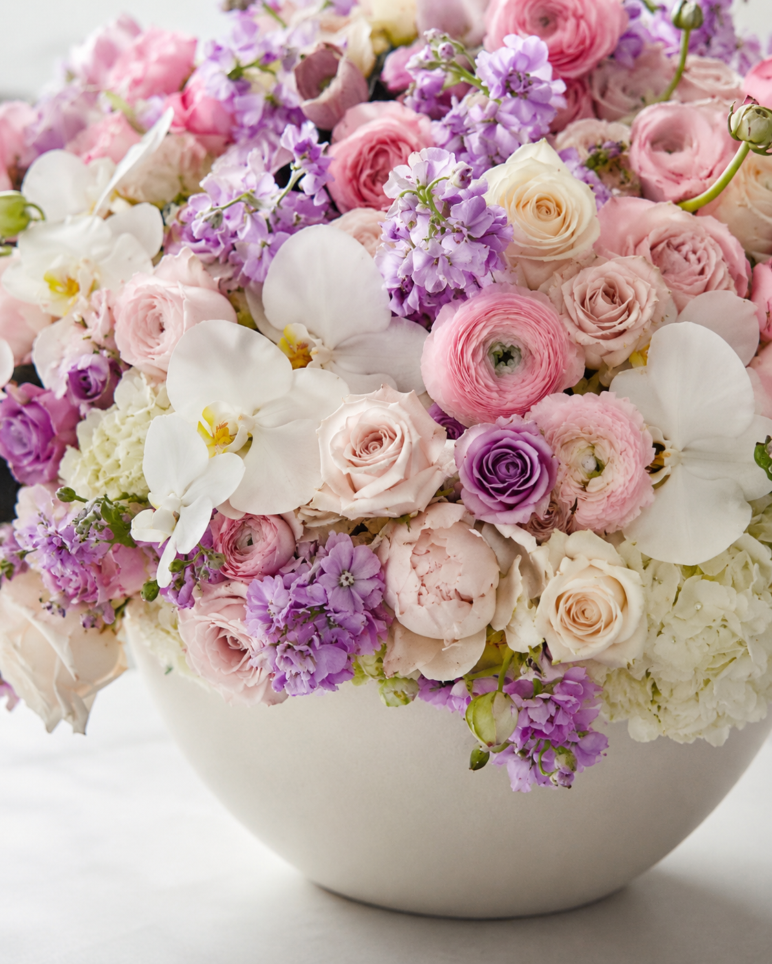 Close-up of Rose Garden arrangement with pink ranunculus, blush roses, white orchids, lavender stock flowers, hydrangeas, and soft greenery | Zelena Flora | Los Angeles