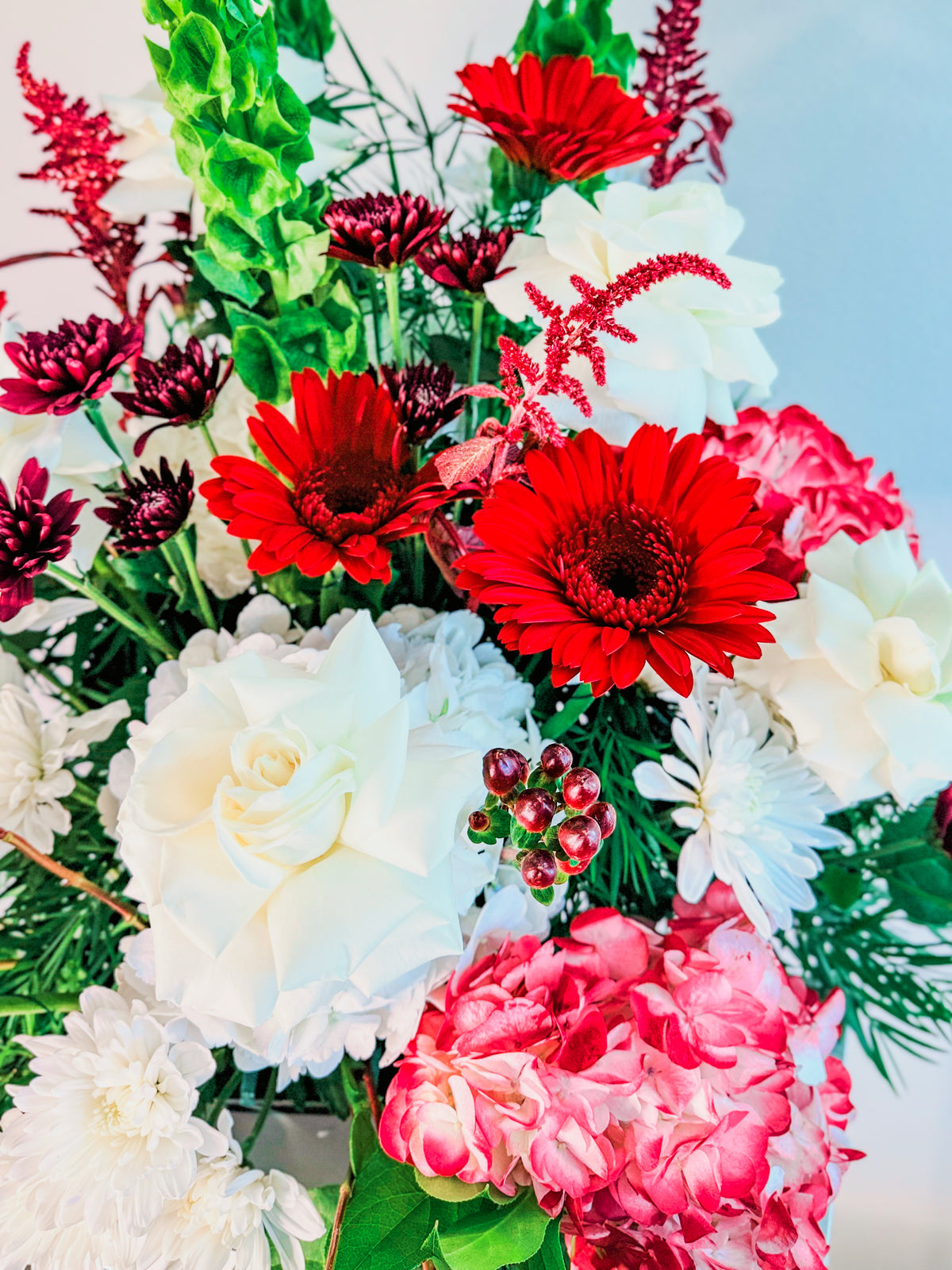 Floral Fanfare flower detail showing red gerberas, white rose petals, pink hydrangeas and burgundy accents.