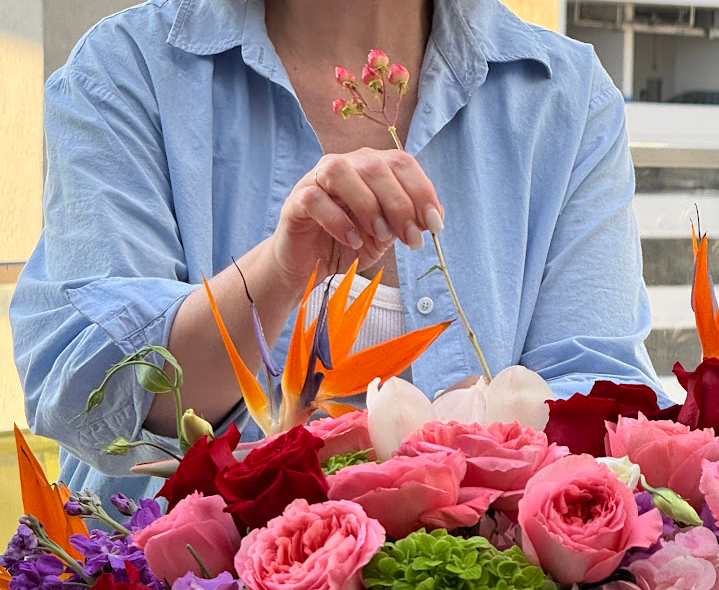 Person arranging flowers with a focus on vibrant colors and textures.