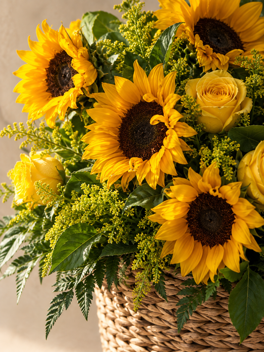 Close detail of irregular sunflower petals, yellow rose, solidago and woven basket with deep flower shadows