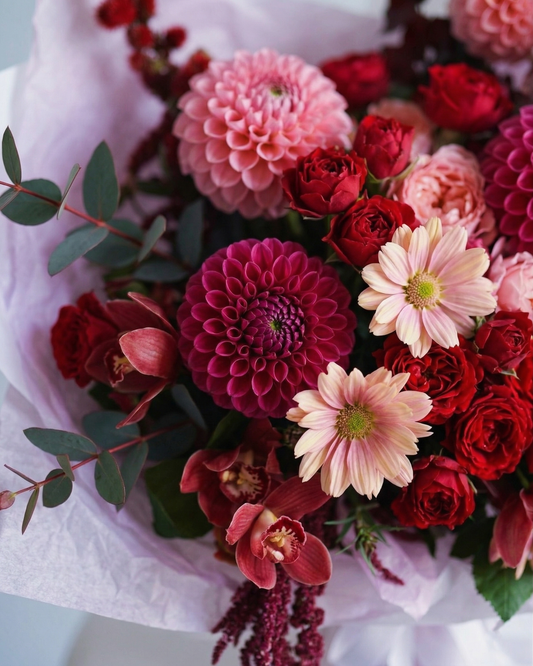Bouquet of red and pink flowers with green leaves on a white background