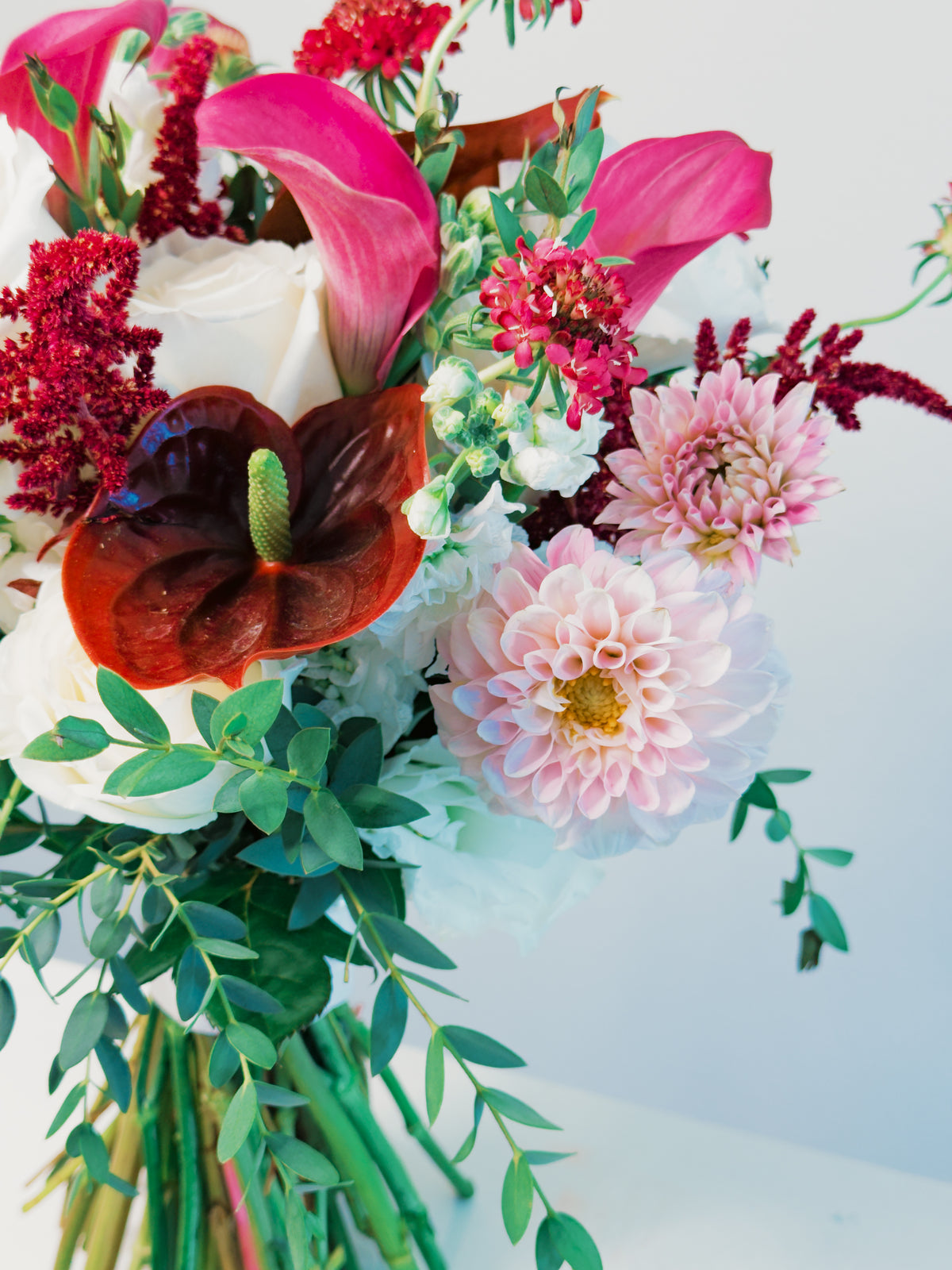 Angled detail of Passion Promise showing blush dahlias, burgundy anthurium and curved mauve calla lilies | Zelena Flora | Los Angeles