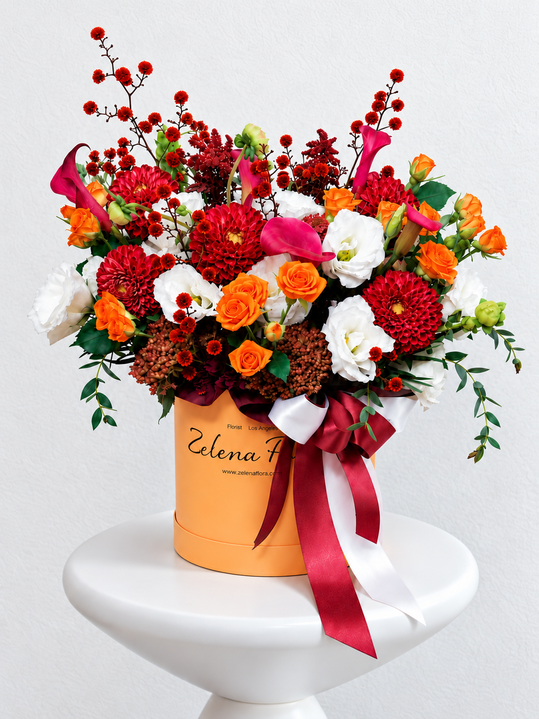 Radiant Rhythm flower box with red dahlias, orange roses, pink calla lilies and white lisianthus, finished with burgundy and white ribbons.