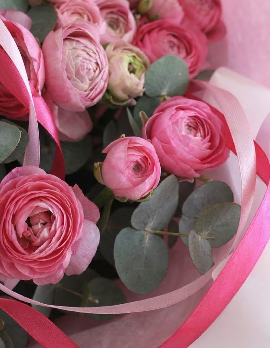 Bouquet of pink flowers with green leaves and pink ribbons.