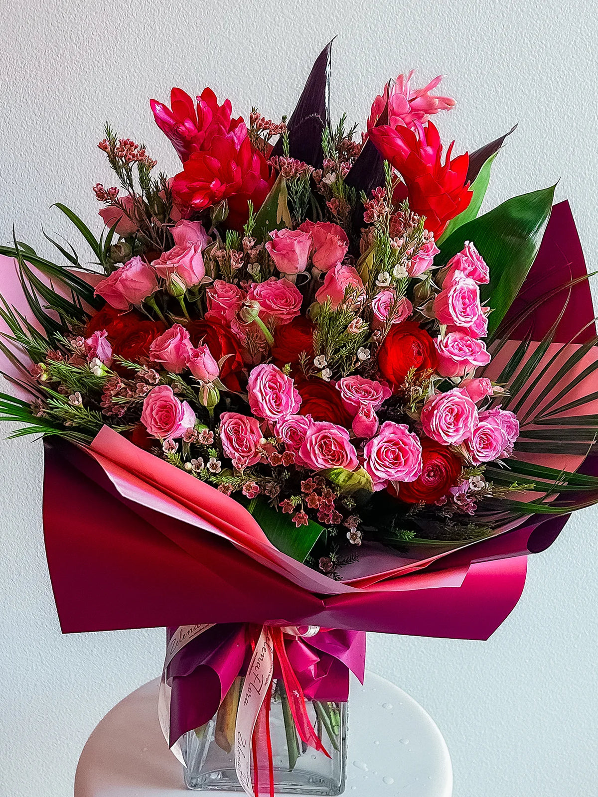 Harmony Halo pink and red bouquet with ranunculus, spray roses, tropical accents, and sculptural greenery | Zelena Flora | Los Angeles